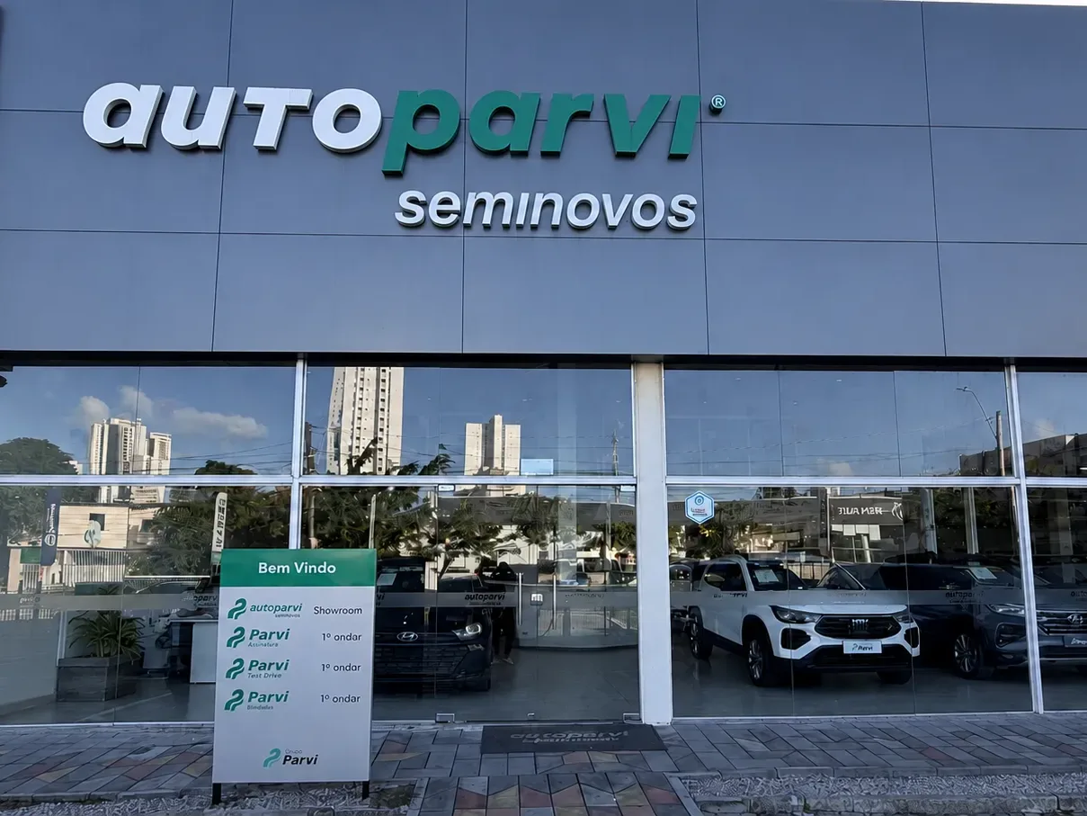 Fachada de uma loja Auto Parvi Seminovos, com carros no showroom